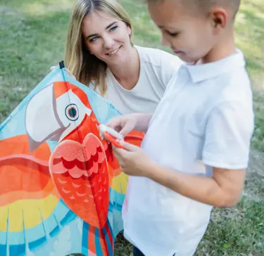 Kisfiú színes sárkánnyal játszik